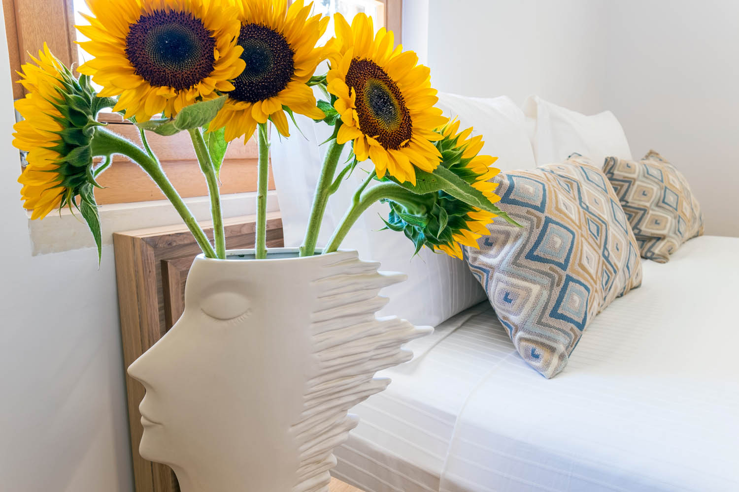 Hotel bedroom, a base with sunflowers at the side of the bed